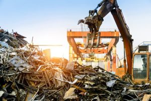 A large crane works in a scrap metal recycling station
