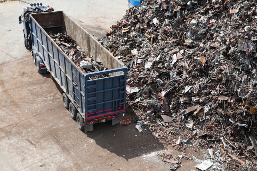 A truck carrying metal scrap next to a pile of scrap metal