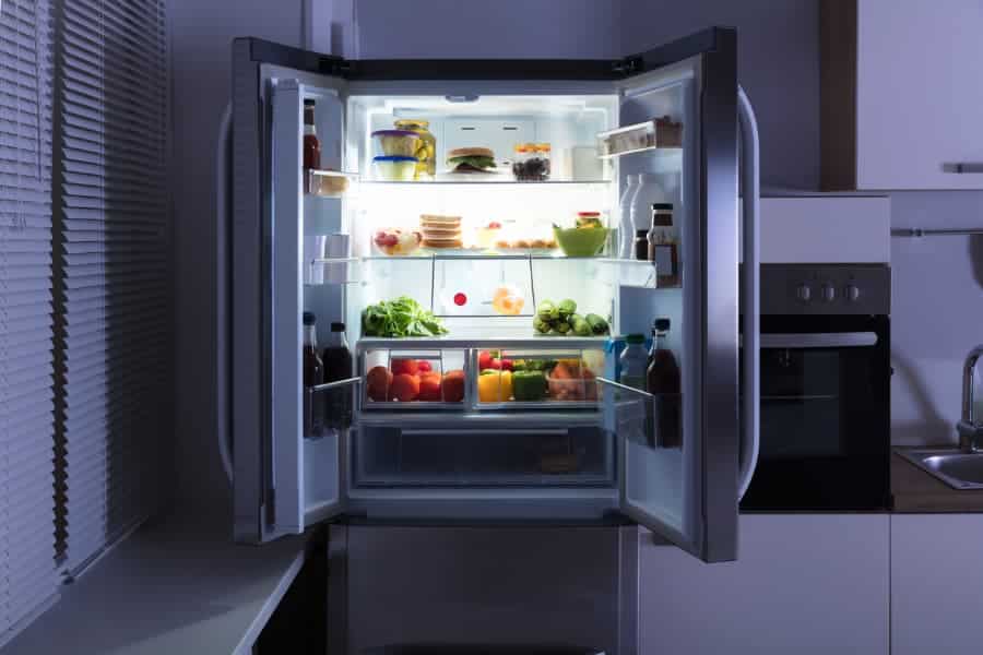 Stainless steel refrigerator doors open showing food inside