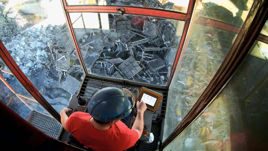 Worker safely operates a crane in a scrap metal recycling yard